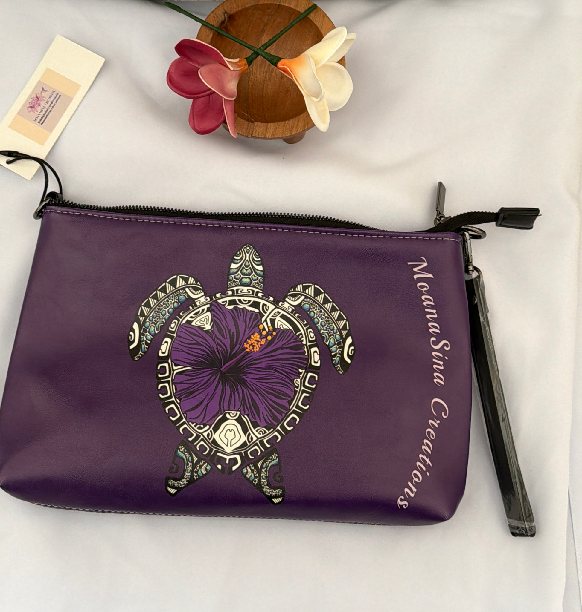 MoanaSina Creations purple faux leather clutch with a sea turtle and hibiscus design, wrist strap.